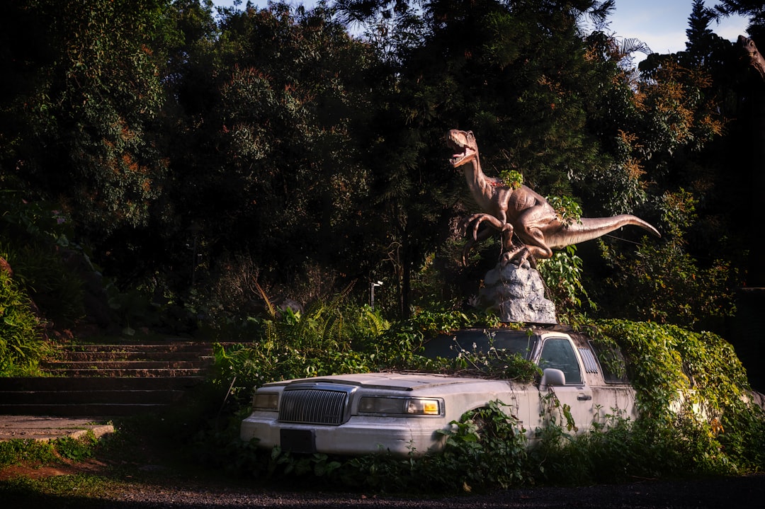 Dinosaur statue on overgrown car in jungle