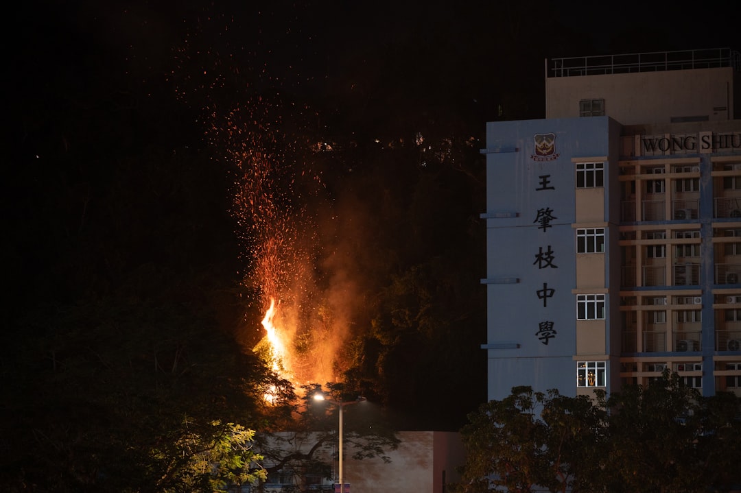Flames erupt next to a building at night.