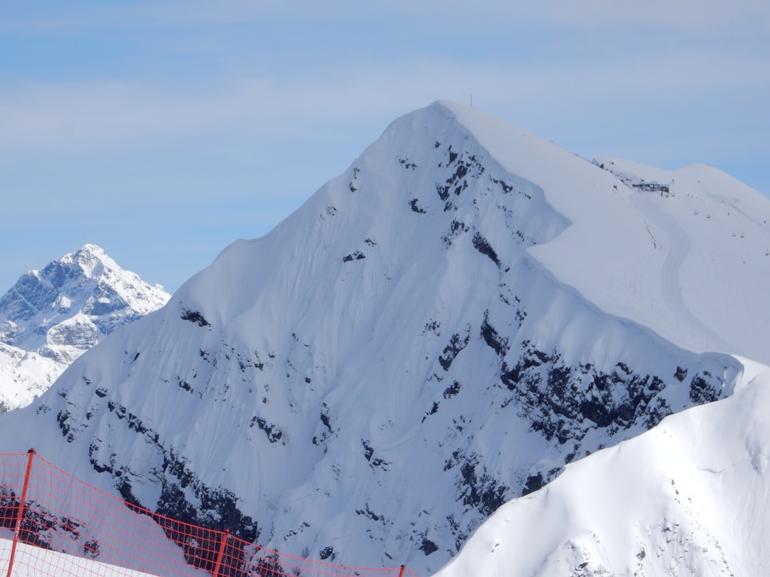 a mountain covered in snow with a fence in the foreground